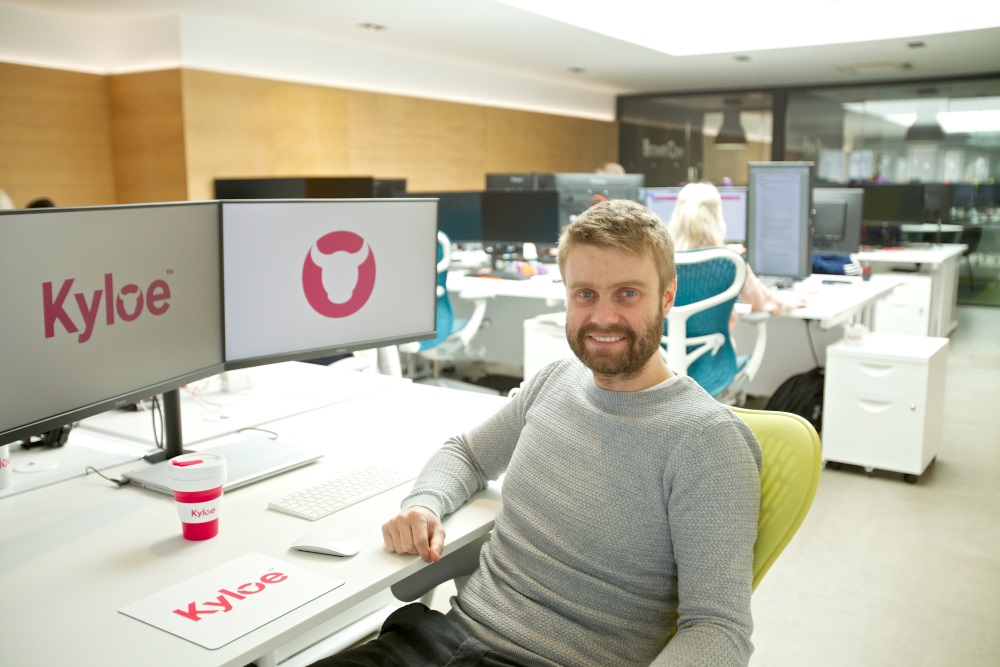 Kyloe staff sitting in front of double screen showing company logo