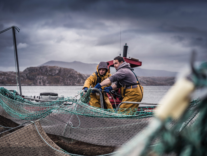 two workers hauling nets on a fish farm